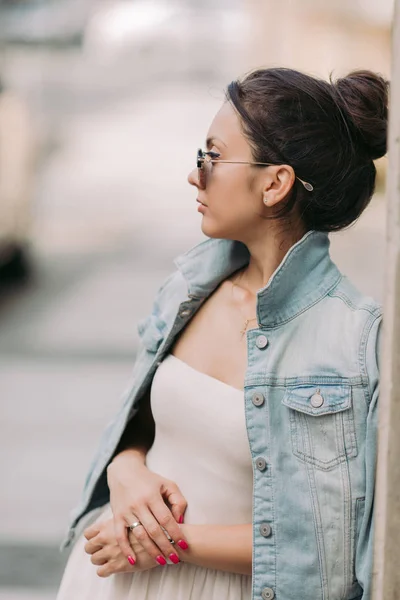 Atractiva mujer en gafas de sol y vestido blanco pasea por las calles de la ciudad en un día soleado — Foto de Stock