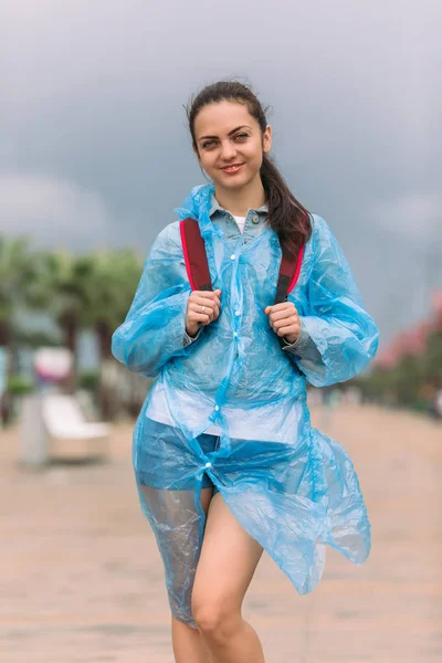 Turista mujer en impermeable con mochila sonriente — Foto de Stock