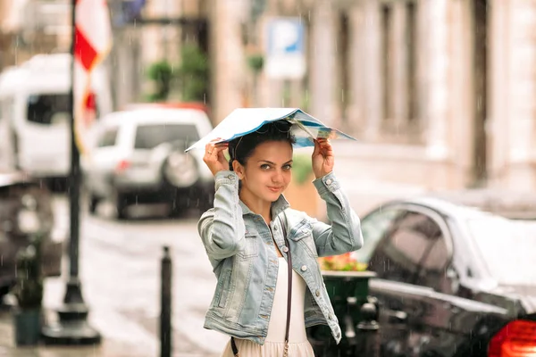 Mulher com mapa caminha pela cidade velha no dia chuvoso — Fotografia de Stock