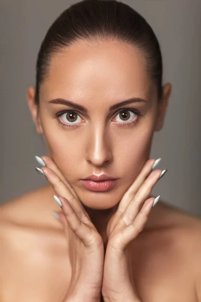 Mooie vrouw Touch eigen gezicht. model met licht naakt make-up — Stockfoto