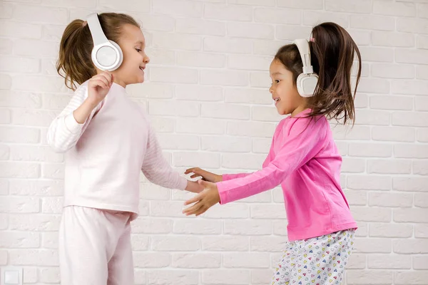 Niñas escuchando la música con los auriculares y bailando en la cama . —  Fotos de Stock