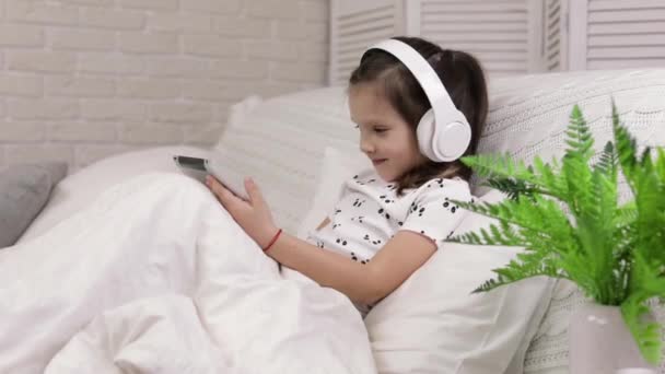 Little child baby girl listening to the music with headphones — Stock Video