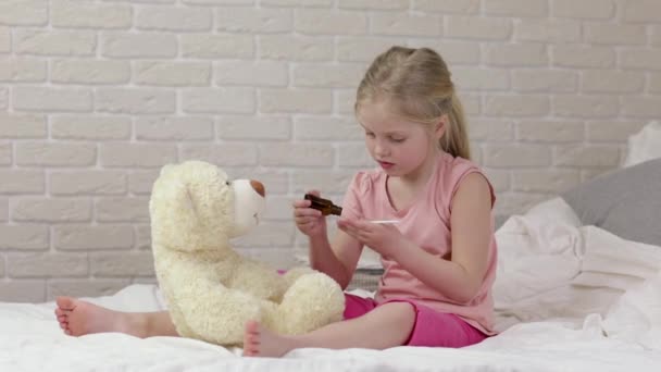 Cute child girl playing doctor with teddy bear — Stock Video