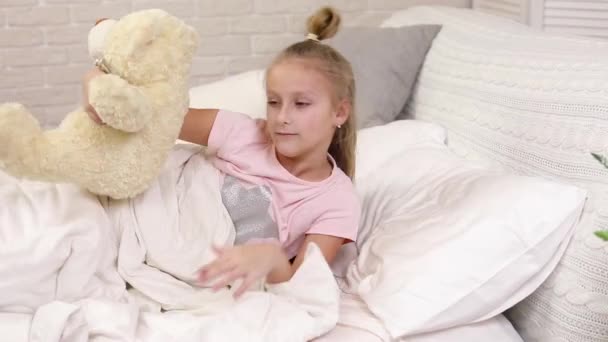 Милая маленькая девочка просыпается от сна в постели — стоковое видео