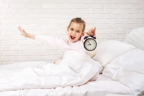 Petite fille en pyjama avec horloge — Photo