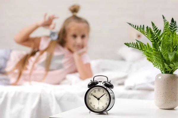 Kis lány pizsama órával — Stock Fotó