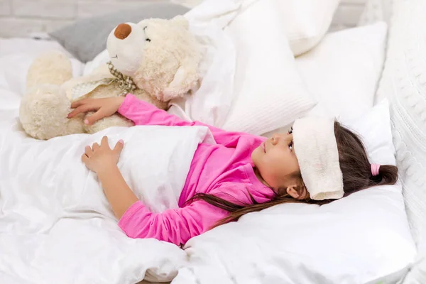 Enfermo frío niño niña se encuentra en la cama —  Fotos de Stock