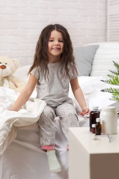 Маленькая больная девочка лежит в постели с термометром — стоковое фото