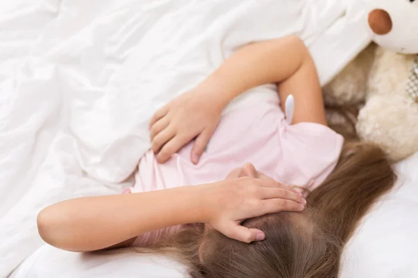 Sick little girl lying in bed with thermometer — Stock Photo, Image