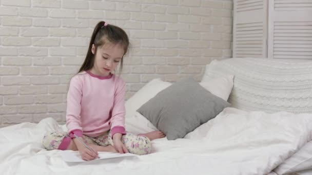 Bonito menina desenho imagens enquanto deitado na cama . — Vídeo de Stock