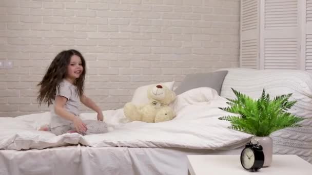 Прелестная счастливая маленькая девочка играет с плюшевым мишкой — стоковое видео