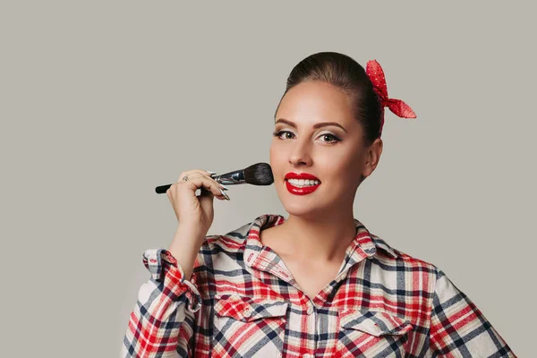 Pin-up girl tenant une brosse à maquillage. femme appliquant blusher . — Photo