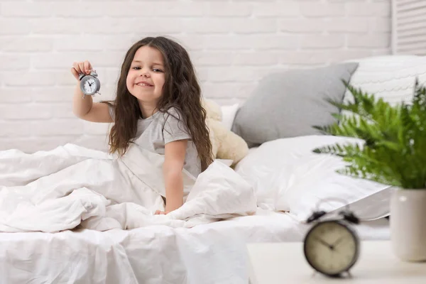 Little girl in pyjamas with clock