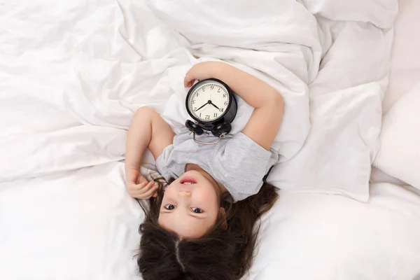 Kleines Mädchen im Pyjama mit Uhr — Stockfoto