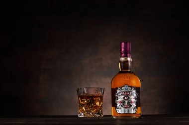 Dnipro, Ukrayna - 18 Haziran 2019: Chivas Regal viski şişesi ve ahşap masa üzerinde buz küpleri ile cam