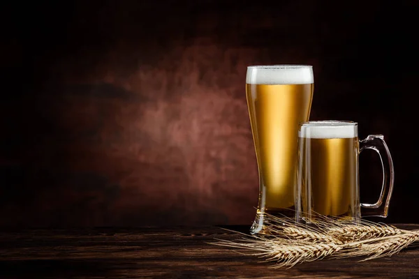 Dois copos de cerveja dourada fria e espiguetas de trigo — Fotografia de Stock