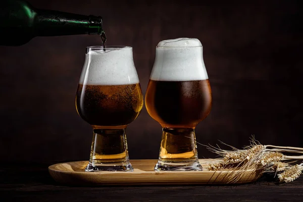 Dois copos de cerveja dourada fria e espiguetas de trigo — Fotografia de Stock