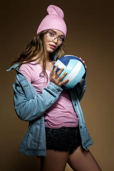 Chica en jeans, un sombrero rosa y gafas con estilo con una pelota —  Fotos de Stock