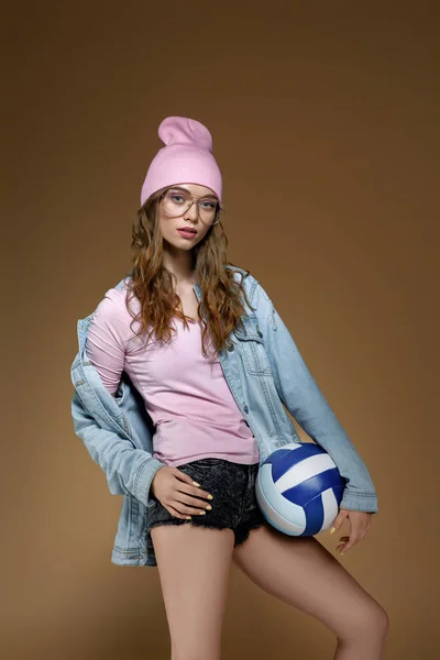 Kot pantolon kız, pembe bir şapka ve bir top ile şık gözlük — Stok fotoğraf