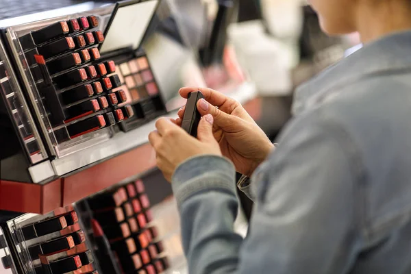 Female customer testing lipstick in make-up shop