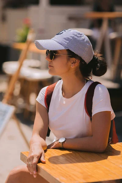 Joven chica turista con una mochila se sienta en una mesa — Foto de Stock