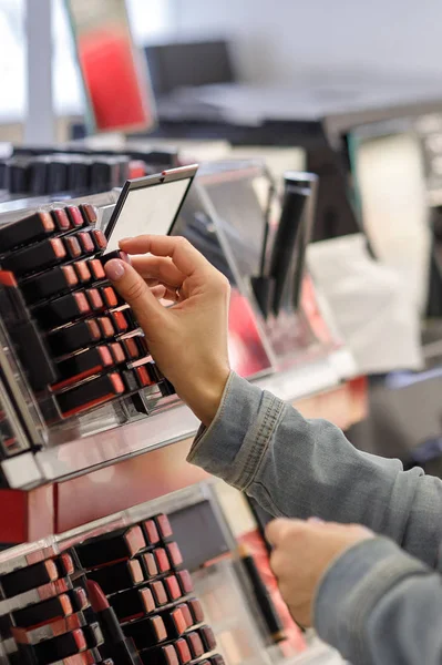 Female customer testing lipstick in make-up shop