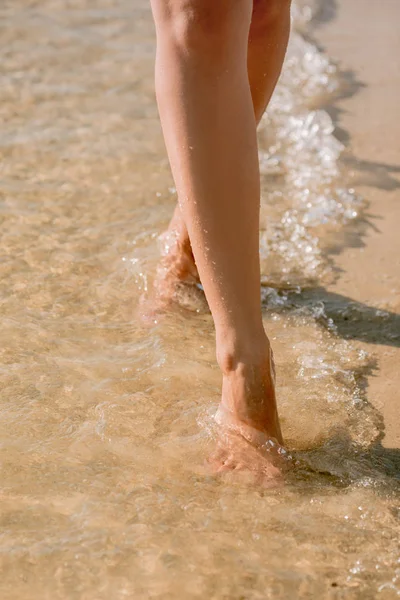 Gambe di donna a piedi sull'acqua di mare — Foto Stock