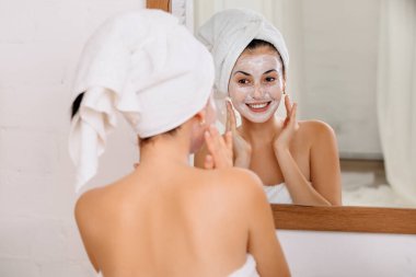 Kadın yüzüne maske takıyor.