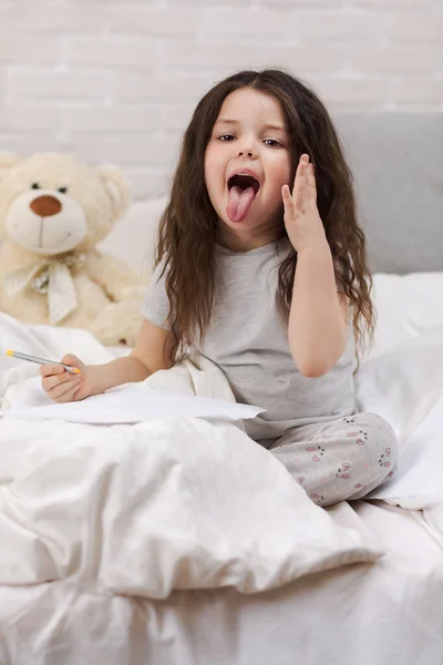 귀여운 어린 소녀 그림 그림 동안 거짓말 에 침대 — 스톡 사진