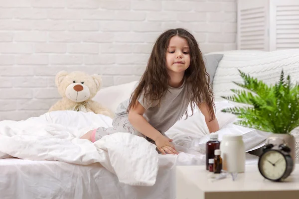 Маленькая больная девочка лежит в постели с термометром — стоковое фото