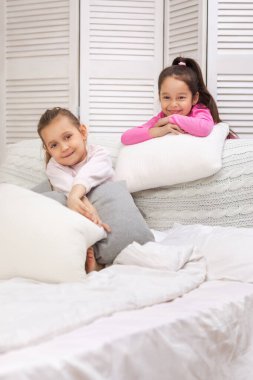 yatak odasında oynayan iki mutlu sevimli çocuk kız.
