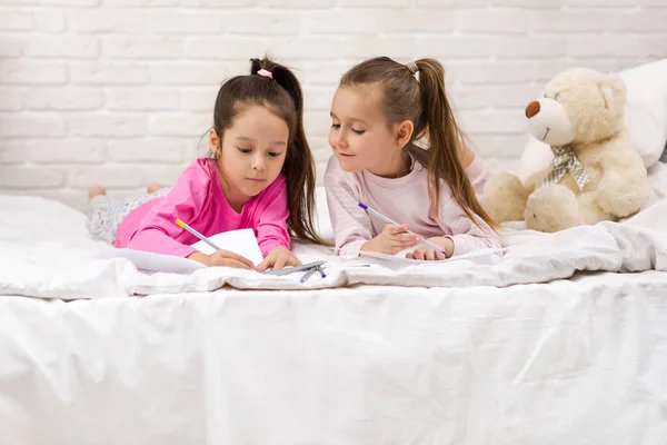 Barn ritning bilder medan liggande på sängen. — Stockfoto