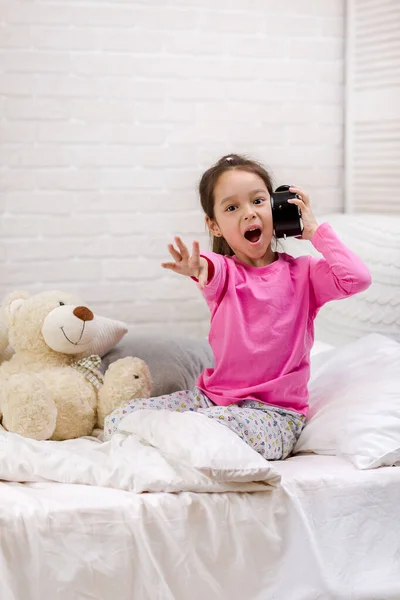 Kis lány pizsama órával — Stock Fotó
