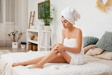 Kadın bacaklarına krem sürüyor.