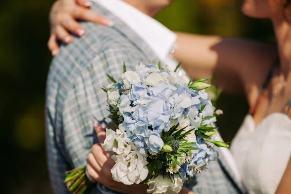 Braut und Bräutigam halten Hochzeitsstrauß — Stockfoto