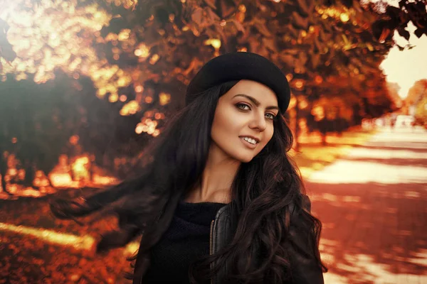 Donna in cappello nero sullo sfondo delle foglie autunnali . — Foto Stock