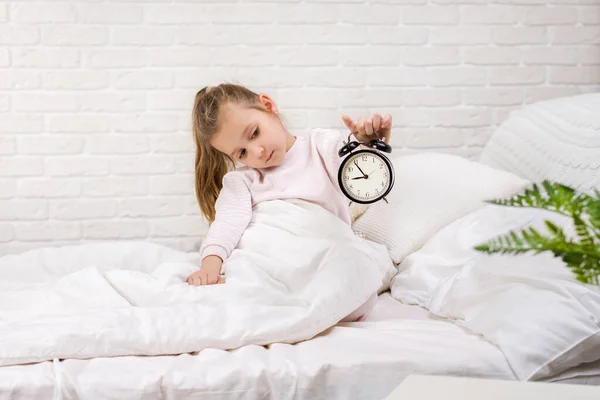 Маленька дівчинка в піжамах з годинником — стокове фото
