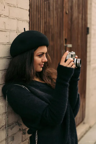 Woman holding retro camera and taking picture — Stock Photo, Image
