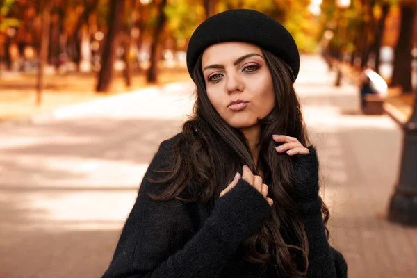 Vrouw met zwarte hoed op de achtergrond van herfstbladeren. — Stockfoto