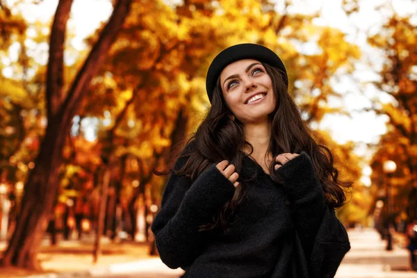 Mujer en sombrero negro en el fondo de las hojas de otoño . — Foto de Stock