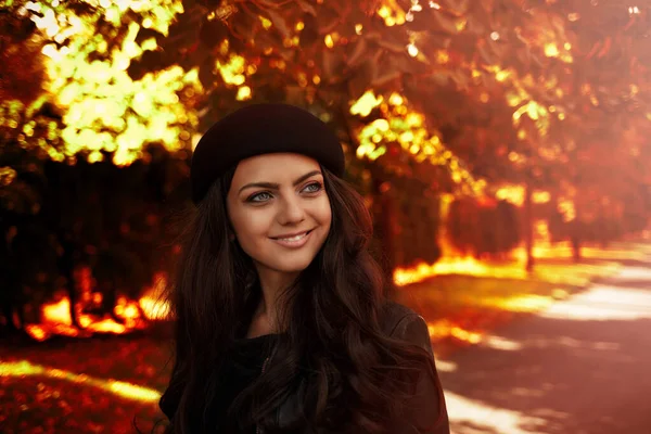 Sonbahar yapraklarının arka planında siyah şapkalı kadın. — Stok fotoğraf
