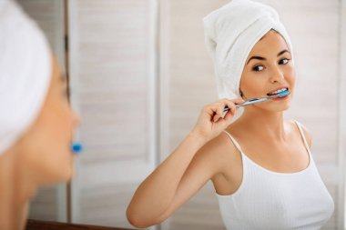 Güzel, genç bir kadın dişlerini fırçalıyor.