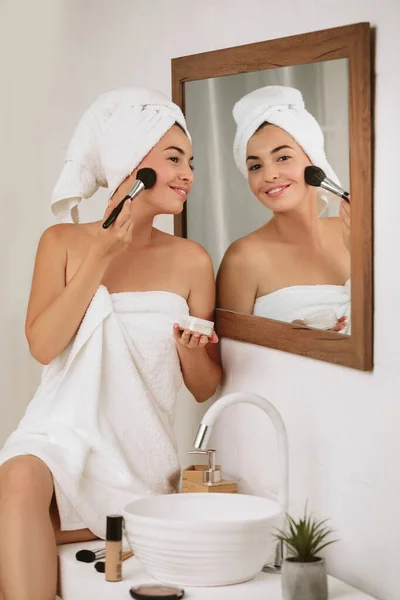 Mulher aplicando maquiagem no rosto em casa — Fotografia de Stock