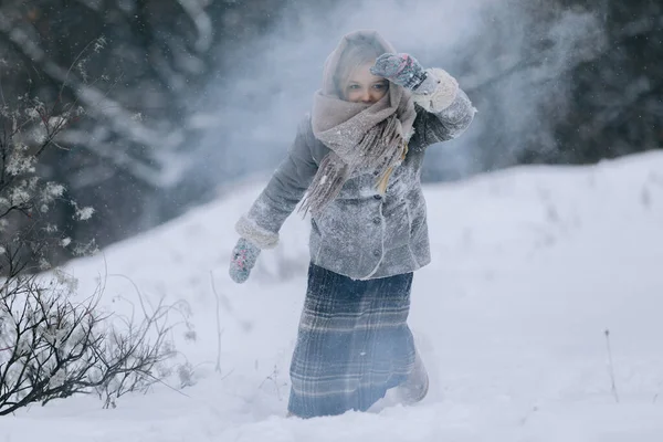Söt liten flicka i skogen på vintern. det snöar — Stockfoto