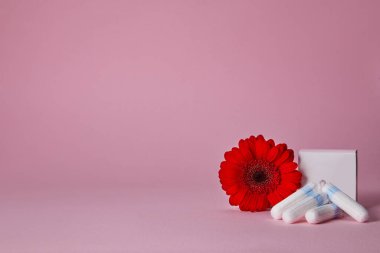 Regl tamponları ve pembe arka planda izole edilmiş kırmızı çiçek, üst manzara. Boşluğu kopyala