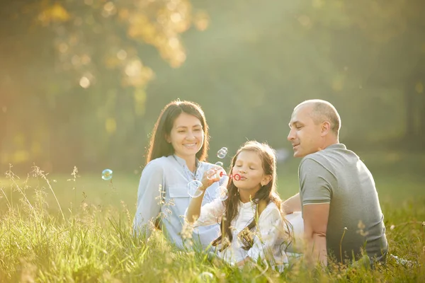 Küçük kızla mutlu bir aile sabun köpüğü üflüyor — Stok fotoğraf