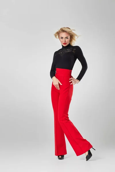 blonde woman in black shirt and red pants