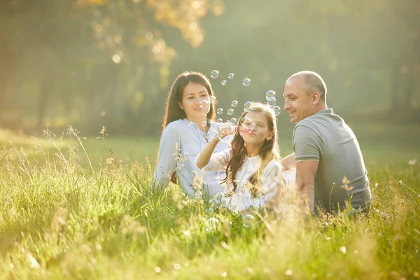Glückliche Familie mit Kind pustet Seifenblasen — Stockfoto