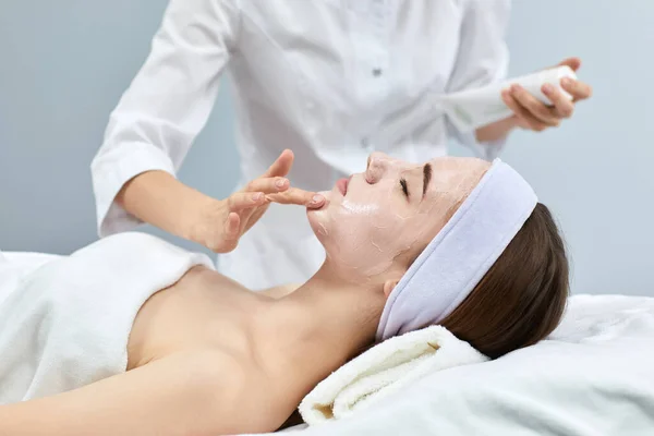 Beautician applies the mask to the face of woman — Stock Photo, Image