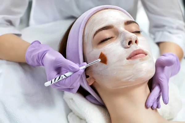 Beautician applies the mask to the face of woman — Stock Photo, Image